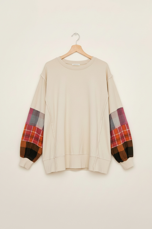 Cream patchwork-sleeve top displayed on a wooden hanger
