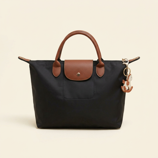 Black nylon tote with brown handles and flap on a plain ivory background