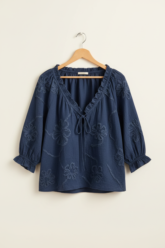 Navy embroidered blouse on a wooden hanger